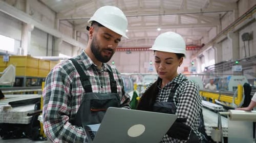 Industrial Engineers Collaborating on Laptop in Factory Setting