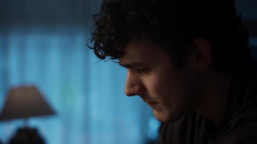 Contemplative Young Man Looking Upward in Dimly Lit Room