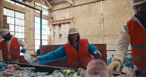 A Trio of Workers at a Waste Recycling Plant People in Uniform Sort Through Plastic Bottles