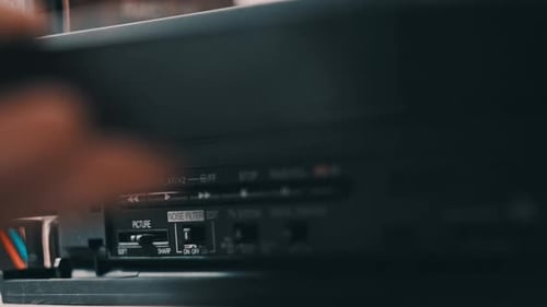 Hand interacts with black VCR machine close up