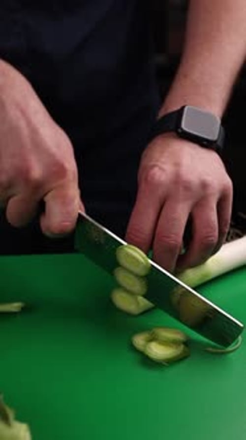 Adult Hands Slicing Leek on Cutting Board