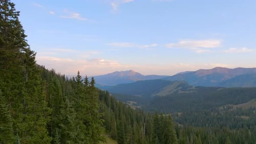 Aerial of mountains with pull back over and through trees in the Colorado Rockies.