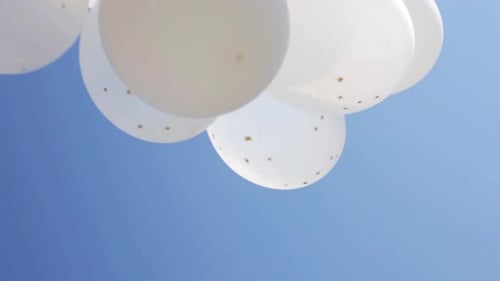 White helium balloons floating freely in a beautiful blue summer sky