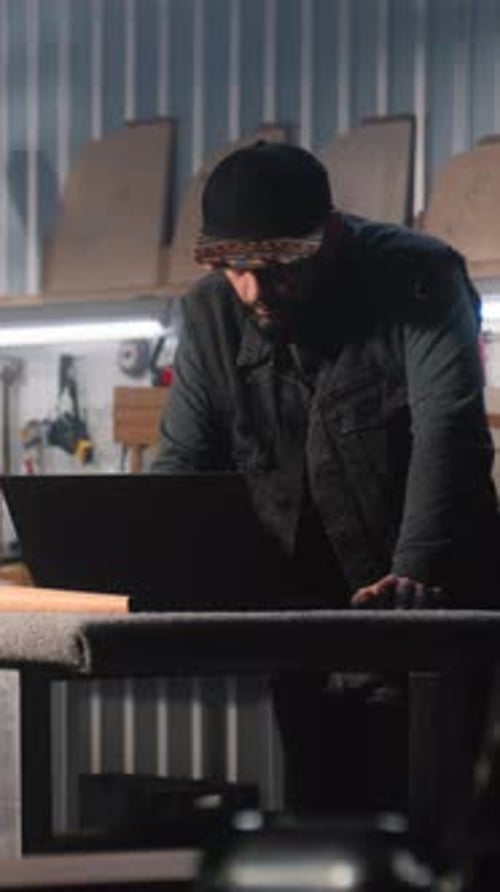 Male Carpenter Uses Digital Tablet and Laptop in Furniture Workshop