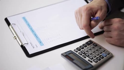 Businessman calculates finances in office workplace technology and papers closeup