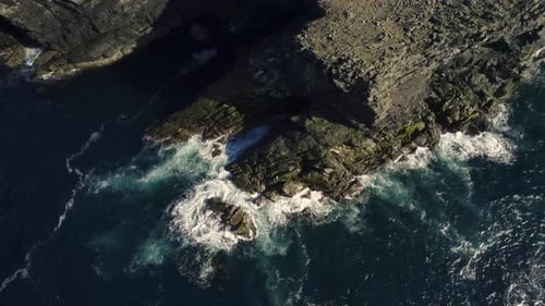 Aerial view of rugged cliffs and ocean waves, Scotland.