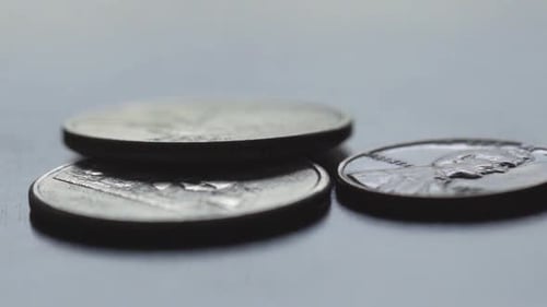 Shallow depth of field of US currency two quarters and a penny in natural light, camera pan right in