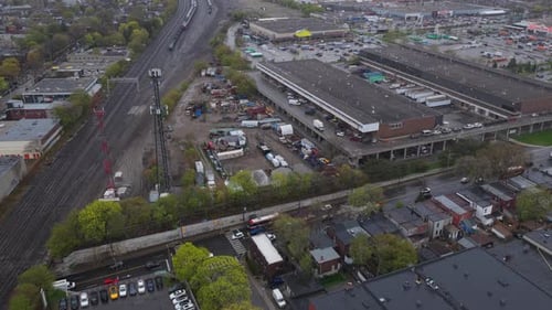 Flug über einen Güterzug im Industriegebiet mit Schienenfahrzeugen, die an bewölkten Tagen auf Straßen fahren