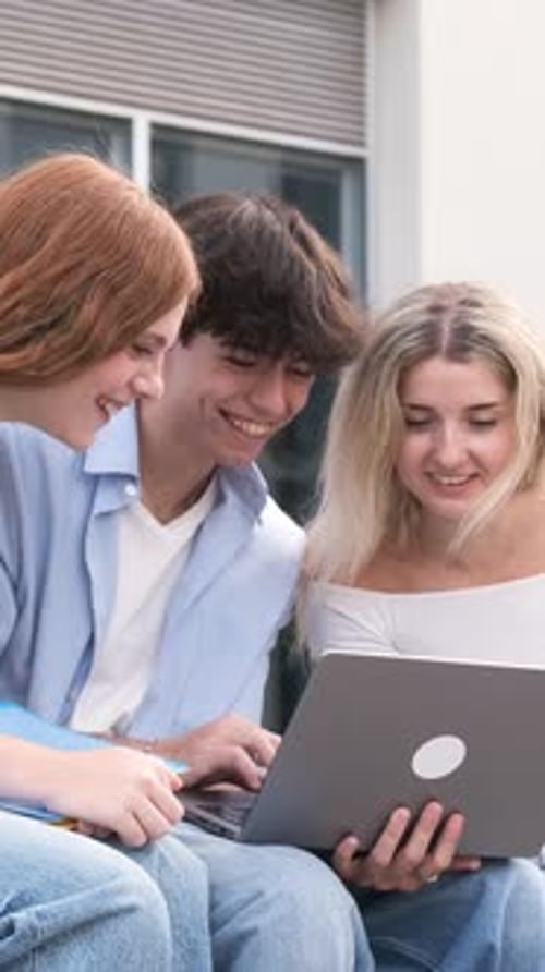 Smiling Students Study Together on Laptop Outdoors