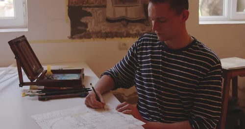 Artist Drawing a Design at a Table Indoors