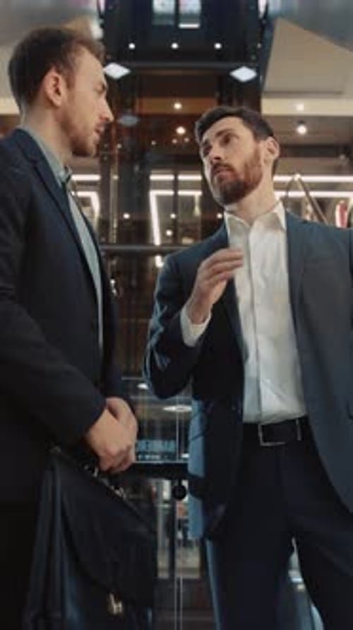 Two Businessmen Shake Hands and Discuss Business Indoors