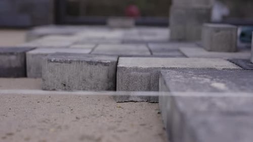 Worker Positioning Concrete Paving Block During Pavement Installation