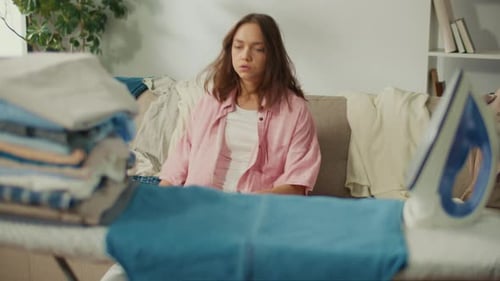 Tired Young Woman Falls on the Sofa From Weakness After Ironing the Laundry