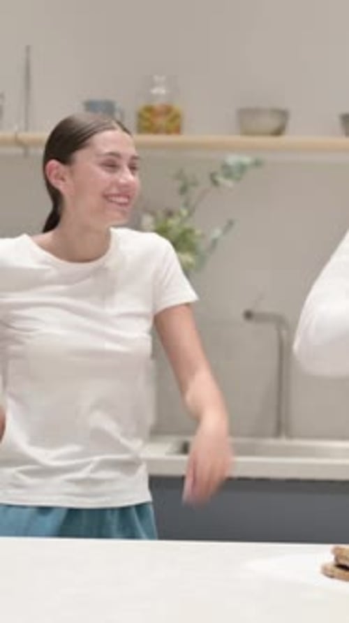 Cheerful Woman Dances in Kitchen Wearing a White T-Shirt