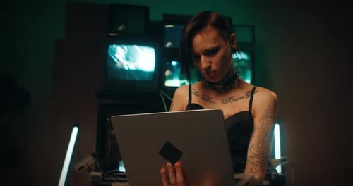 Tattooed Woman Working on Laptop in Dark Room