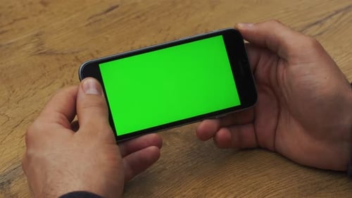 Man Using Horizontal Smartphone with Green Screen Closeup Shot of Man's Hands with Mobile Phone