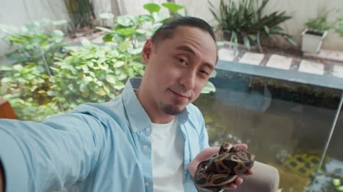 Punto de vista de un alegre propietario tomándose una selfie con Python Snake