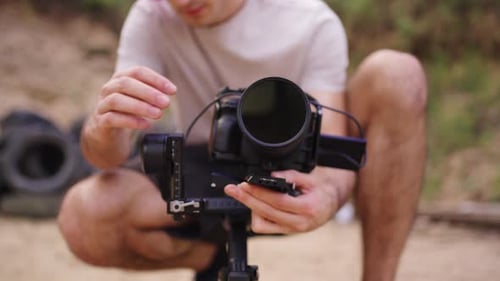 Young Adult Man Adjusting Video Camera Outdoors