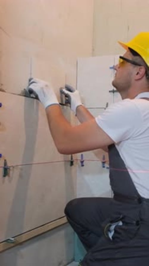 Construction Worker Installing Tiles on a Wall