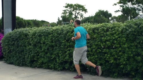 Young man jogging in city park super slow motion training workout