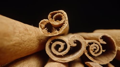 A handful of dried cinnamon sticks on a black background. Dolly slider extreme close-up