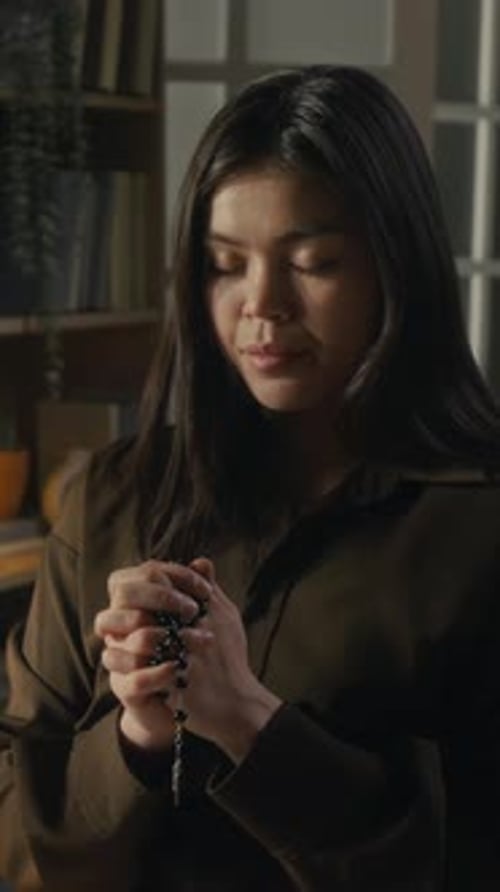 Woman Holding Rosary and Praying Inside Home