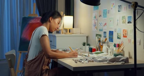 Asia lady drawing picture on sketchbook create artwork cozy workshop in home at night.