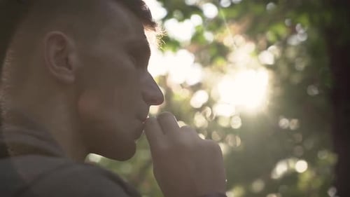 Un jeune homme fume une cigarette dans un parc de la ville. Portrait. coucher de soleil.