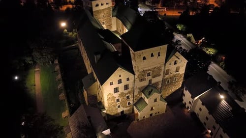 Aerial descending shot in front of the Turku castle, nighttime in Abo, Finland