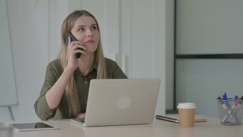 Woman Talking on Smartphone at Office Desk