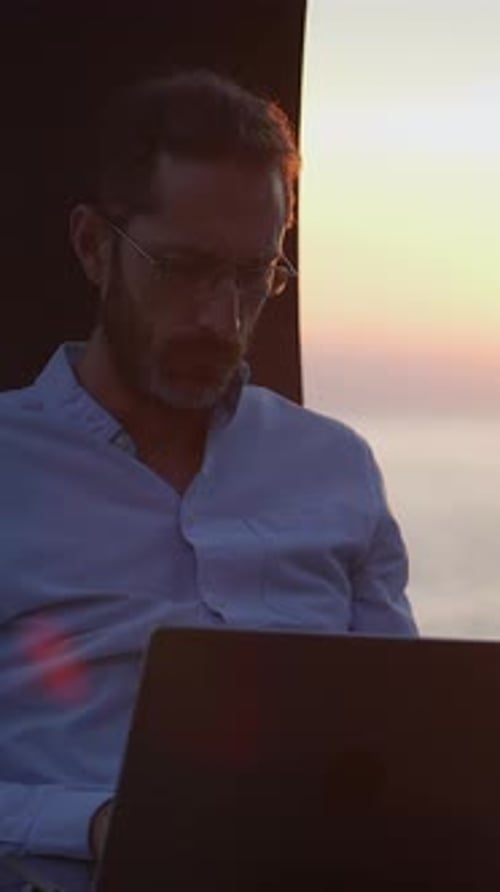 Eine Person, die während eines malerischen Sonnenuntergangs, umgeben von der Schönheit der Natur, an einem Laptop arbeitet