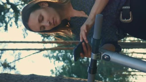 Woman Using Phone with Electric Scooter in Park