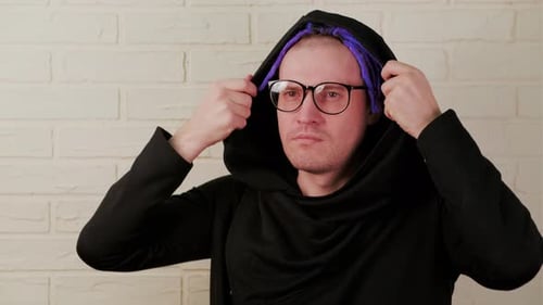 Man Puts on Hooded Sweater Indoors