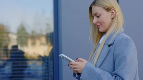 Side View of the Beautiful Woman Multitasking Using a Modern Cellphone While Strolling Outdoors