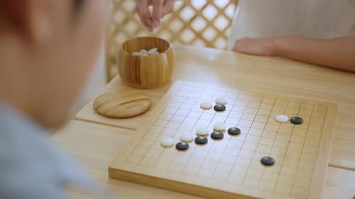 Primer plano de jóvenes jugando al juego de mesa Go durante una competencia en la Comunidad.