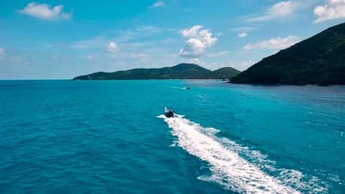 Drone shot of a small boat sailing next to the island.