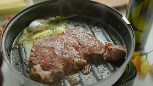 Beef Steak Being Cooked in Grill Pan with Butter, Herbs and Garlic