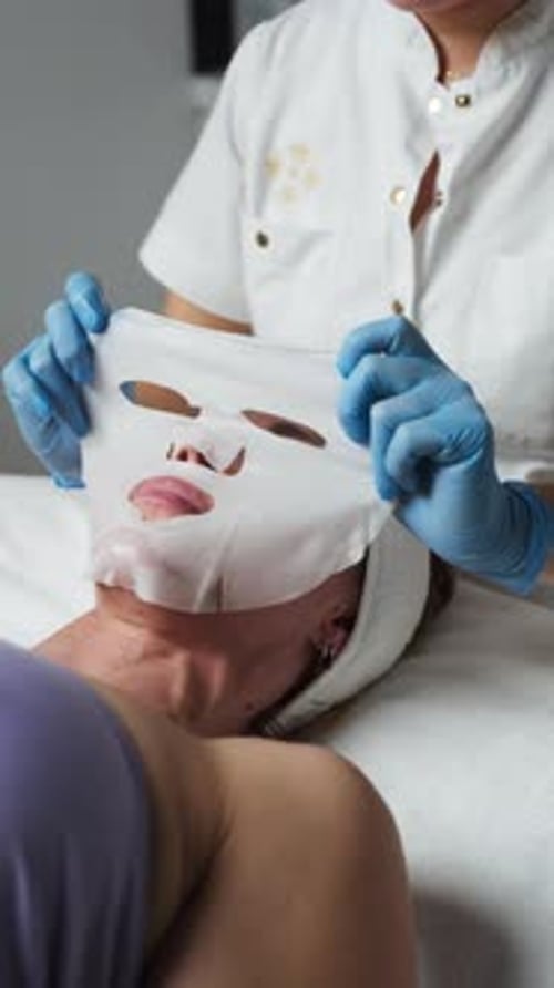A Masseuse Placing a Facial Mask on the Client's Face in a Spa - Close Up