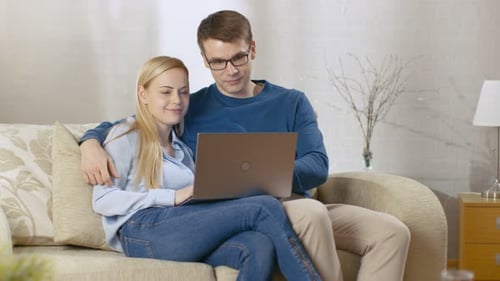 Couple Relaxing on Couch Using Laptop Together