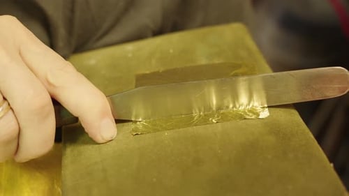 Der Künstler schneidet Blattgold in Stücke, um es auf das Ölgemälde aufzutragen