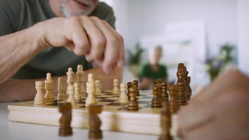 Close Up of Two Senior Friends Playing Chess Indoors, Social Gathering Concept