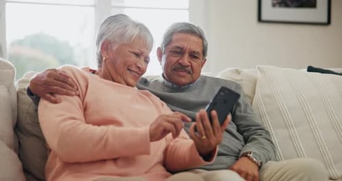 Affectionate Senior Couple Laughing with Smartphone at Home