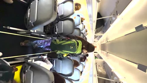Female passenger with backpack walking down the aisle in an aircraft, backpacker boarding a plane