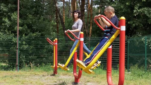 Mother and Son on Street Exercise Machines Go in for Sports