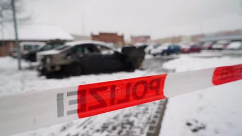 Vandalised car arson police crime scene, on snowy winter city street, rack focus