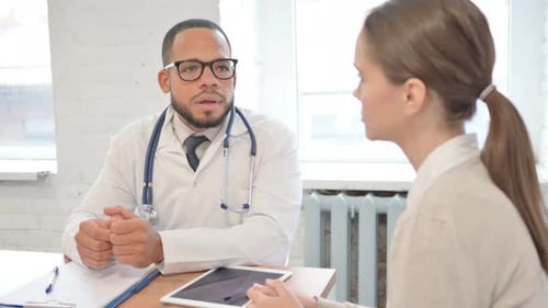 African Doctor Talking with Female Patient in Clinic