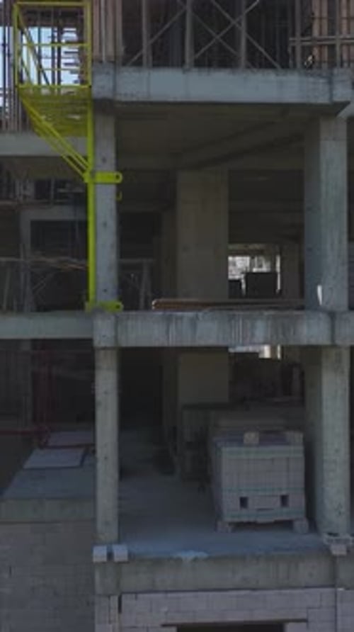 Equipos de vídeo verticales que construyen paredes estructurales y utilizan mezcladoras de concreto en una zona de construcción muy transitada