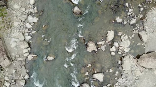 Top down aerial view of pristine river rapids flowing over boulders