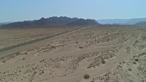 Aerial view of a fast sports car driving down a remote desert road