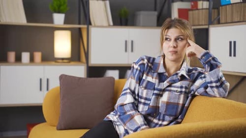 Woman Thinking, Sitting on Couch in Home Interior